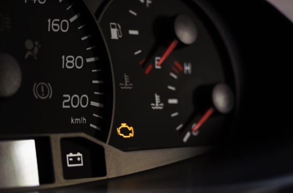 Yellow lit engine error sign on car dashboard close up