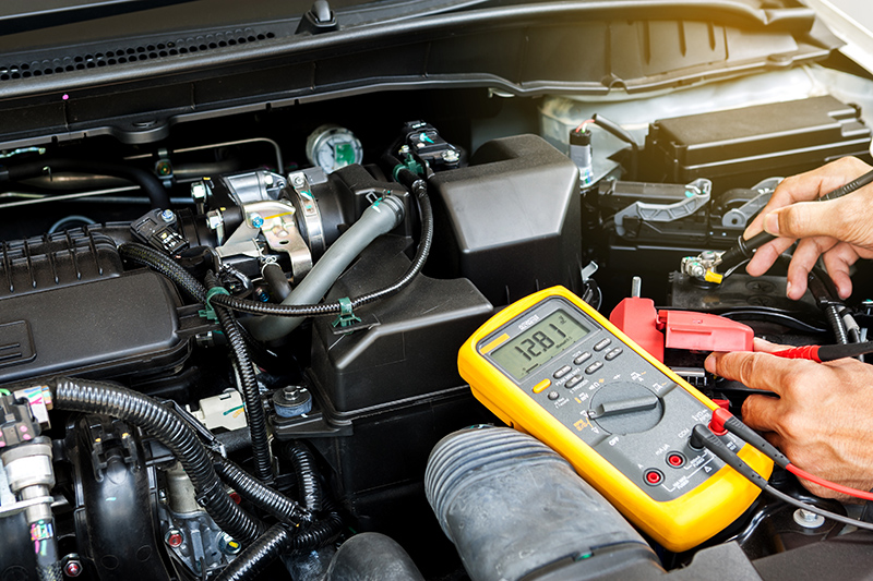 Car mechanic is using a multimeter with voltage range measuremen