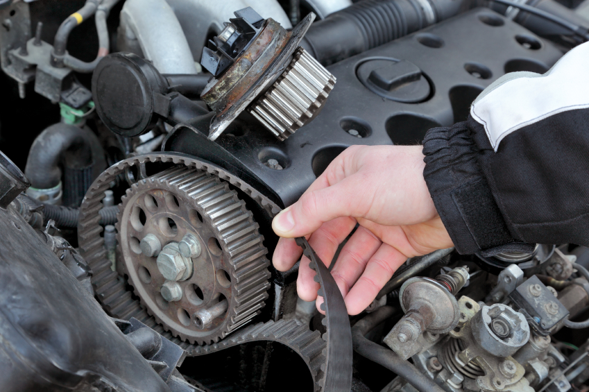 Car mechanic replacing timing belt at camshaft of modern engine